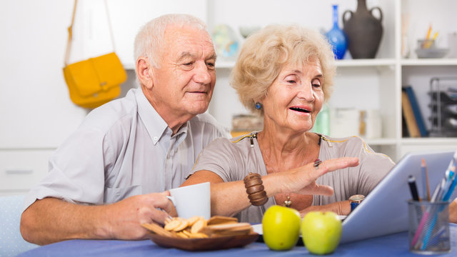 Smiling Senior Couple Surfing Net With Laptop