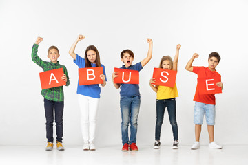 Obraz premium Abuse makes you monster. Group of screaming angry serious children with red banners isolated on white studio background. Education and advertising concept. Protest and children's rights concepts.