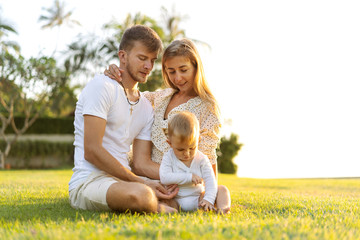 Naklejka na ściany i meble happy family on tropical island at sunset playing with son