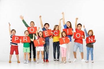 Obraz premium Protection feeling makes calm. Group of happy screaming children or young team with a red banners isolated in white studio background. Education and advertising concept. Social rights concepts.
