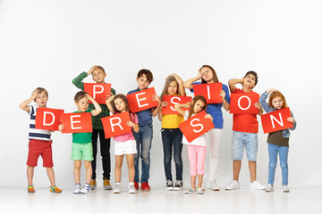 Depression kills your character. Group of saddened and distressed children with red banners isolated on white studio background. Education and advertising concept. Protest, children's rights concepts.
