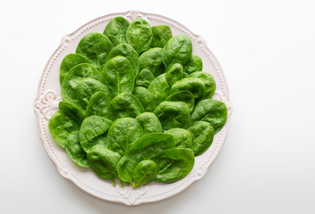 Young leaves of spinach on a plate. Copy space. Detox, a dietary food ingredient - green organic spinach.