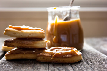 Homemade salted caramel sauce on a wooden serving board. Caramel flows from the spoon. Selective focus.