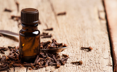 Essential oil of cloves, brown bottle, old wooden background, selective focus
