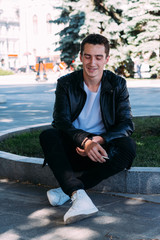 a young guy smokes around a tree in the city.bad habit.smoking in a public place