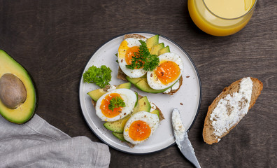 Two toasts with avocado and boiled egg on grain bread at white plate
