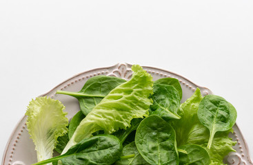 A mixture of spinach leaves and salana leaves on a plate. Selective focus, white background.