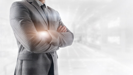 Portrait confident businessman standing with crossed arms over cityscape background. 