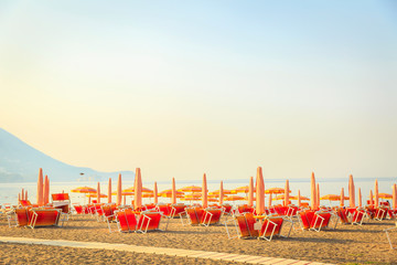 Tropical beach resort hotel background as summer landscape with lounge chairs and parasol in sun rays and calm sea. Tourism and travel, vacation, holiday destination concept © AnnKot
