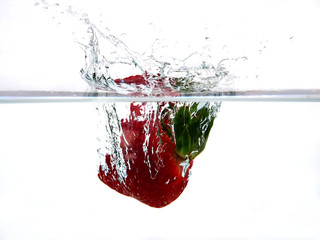 strawberry falling into water with splash isolated on white