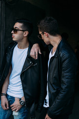 beautiful and attractive guy is standing in the city, posing. near the mirror building. walk around the city in black glasses. communication. meeting friends.
