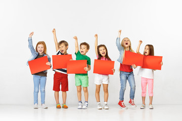 Group of happy smiling children with red empty banners isolated in white studio background. Education and advertising concept