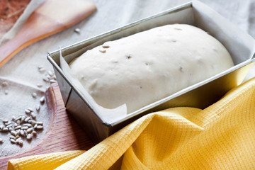 Raw yeast dough in tin form, ready for baking bread with sunflower seeds