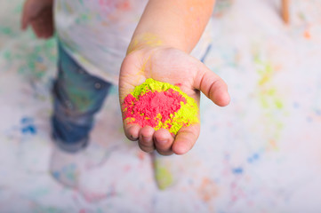 Festival of holi and holidays concept - baby's hand with colored powder.
