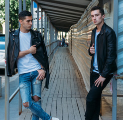 beautiful and attractive guy is standing in the city, posing. near the mirror building. walk around the city in black glasses. communication. meeting friends.