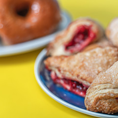 Glazed doughnuts and turnovers on a yellow background.