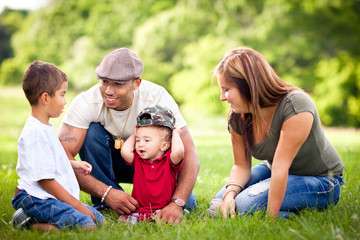 Fototapeta premium Happy Young Family Sitting Together Outside - Color Portrait