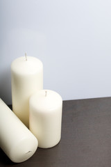 Fototapeta na wymiar Candles white in different sizes. White background turning into dark.