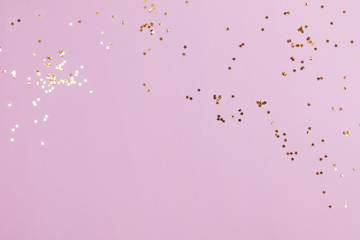 Golden star shaped confetti on pink pastel backdrop.