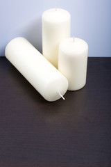 Candles white in different sizes. White background turning into dark.