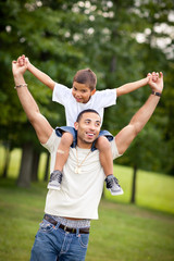 Obraz premium Happy Dad Giving Son Piggyback Ride Outside - Color Portrait