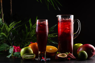 Lemonade blueberry - blackberry in a jug and a glass and fruit on dark wooden background