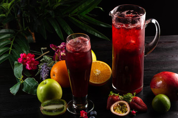 Lemonade blueberry - blackberry in a jug and a glass and fruit on dark wooden background