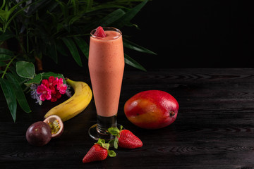 Cocktail with fruits and berries in a tall glass on a dark wooden background