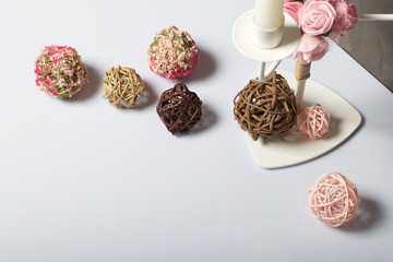 Candles white on a metal candlestick. Nearby are decorative balls, woven from natural materials. Balls of vine and grass.