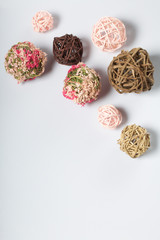 Candle white in color among the decorative balls, woven from natural materials. On a white background.