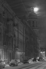 black and white full moon among the clouds above a winter city street