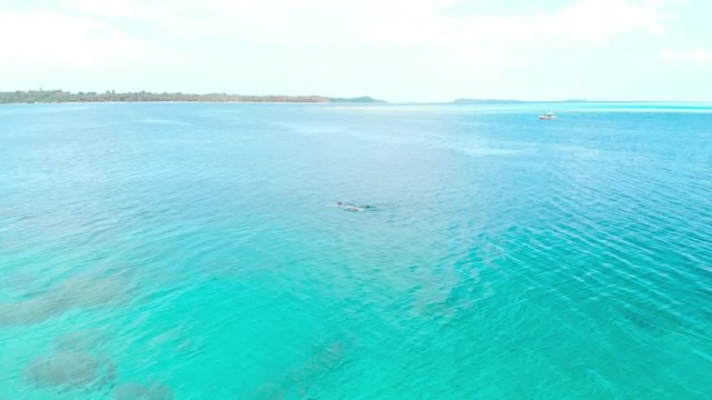 Aerial slow motion: people snorkeling on coral reef tropical caribbean sea, turquoise blue water. Indonesia Banyak Islands Sumatra, tourist diving travel destination.
