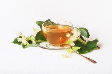 Linden tea on a white table in a glass cup. Flower tea, herbal medicine