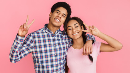 Students showing peace gesture over pink background