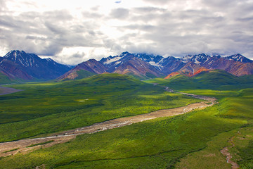 Fototapeta na wymiar With its huge mountains and surrounded by a wonderful biodiversity lies the Denali National Park and Preserve. River, trees and cloud sky. Landscape, fine art. Parks Hwy, Alaska, EUA: July 28, 2018