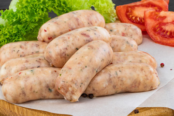 Fresh raw sausage with lettuce and tomato on the wooden background