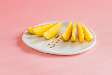 Mango fruit and mango slices on the white plate.