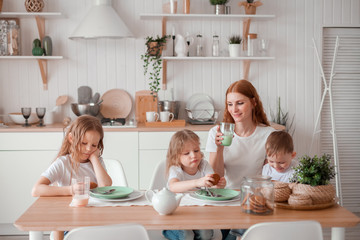 Mom and children are sitting at the table in the kitchen