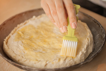 Woman lubricates an pie by egg. Top view