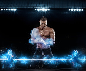 Fototapeta na wymiar Photo of strong muscular bodybuilder athletic man pumping up muscles with barbell on black background with lights. Workout energy bodybuilding concept.