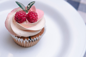 Strawberry cupcakes on white plate, composition with raspberry berries and green leaves