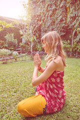 Young woman practicing yoga in tropical garden.