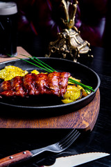 Close up Gourmet Main Dish with Grilled Pork Rib and Fried Potatoes on Black pan. Served on Wooden Board