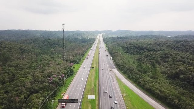 Drone aerial shot from a highway  in Sao Paulo - middle of the forest - showing cars, trucks and traffic