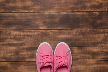 Pink sneakers on wooden background.