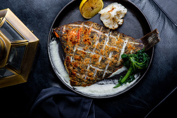 Flounder fillet roasted in a skillet with herbs and lemon