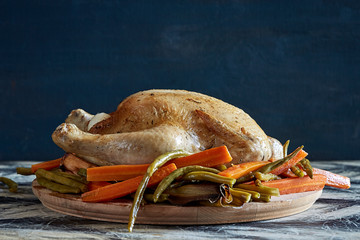 Cooked chicken with vegetables on wooden cutting board