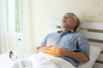 Fototapeta premium Senior male asian suffering from bad pain in his have a stomachache at home - senior healthcare concept