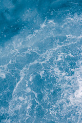 Pale blue sea surface with waves, splash,  foam and bubbles at high tide and surf, abstract background