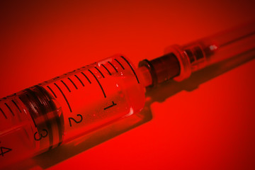 Empty syringe on red background close up